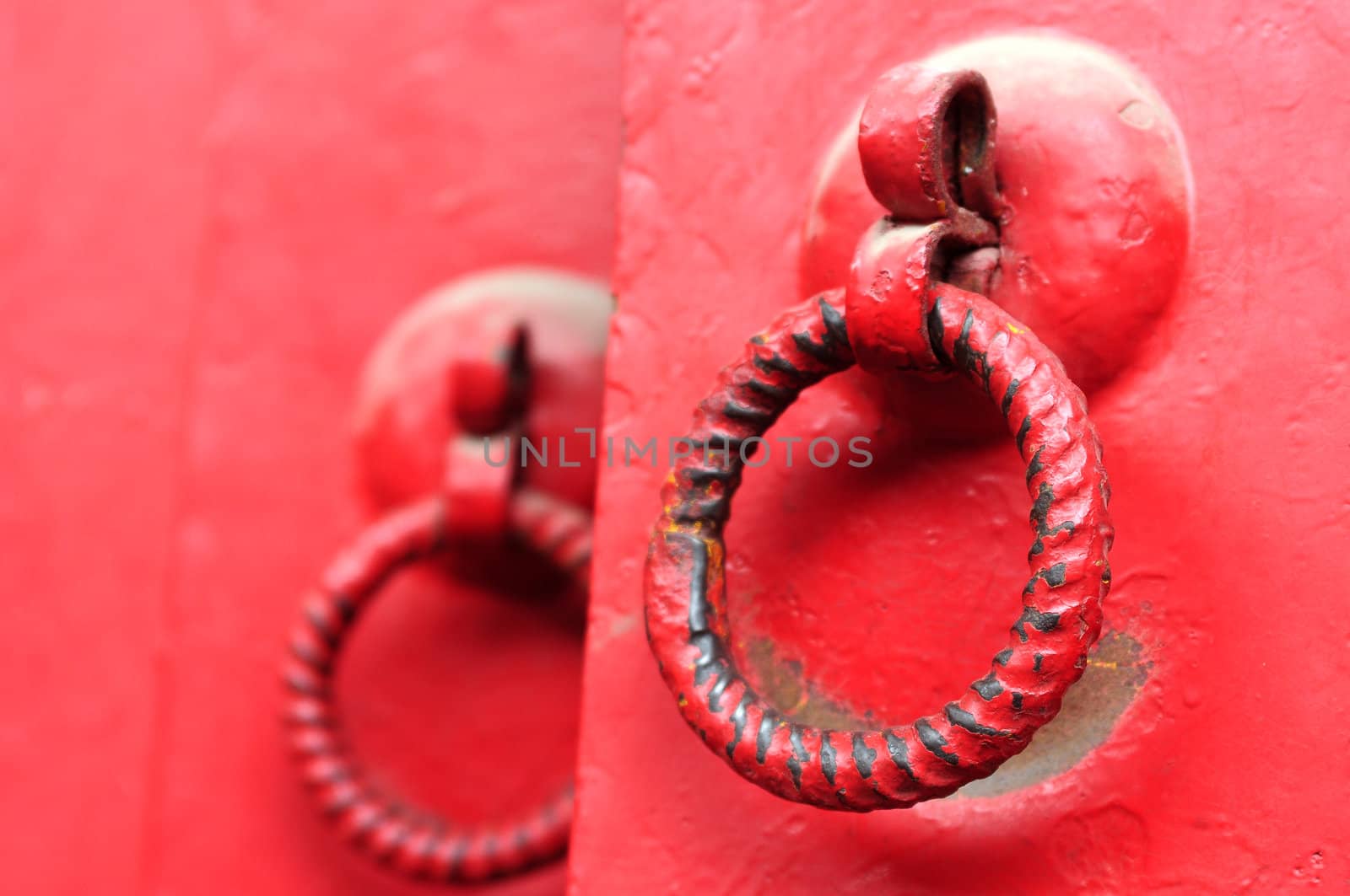 Closeup view of red doors with iron doorknobs