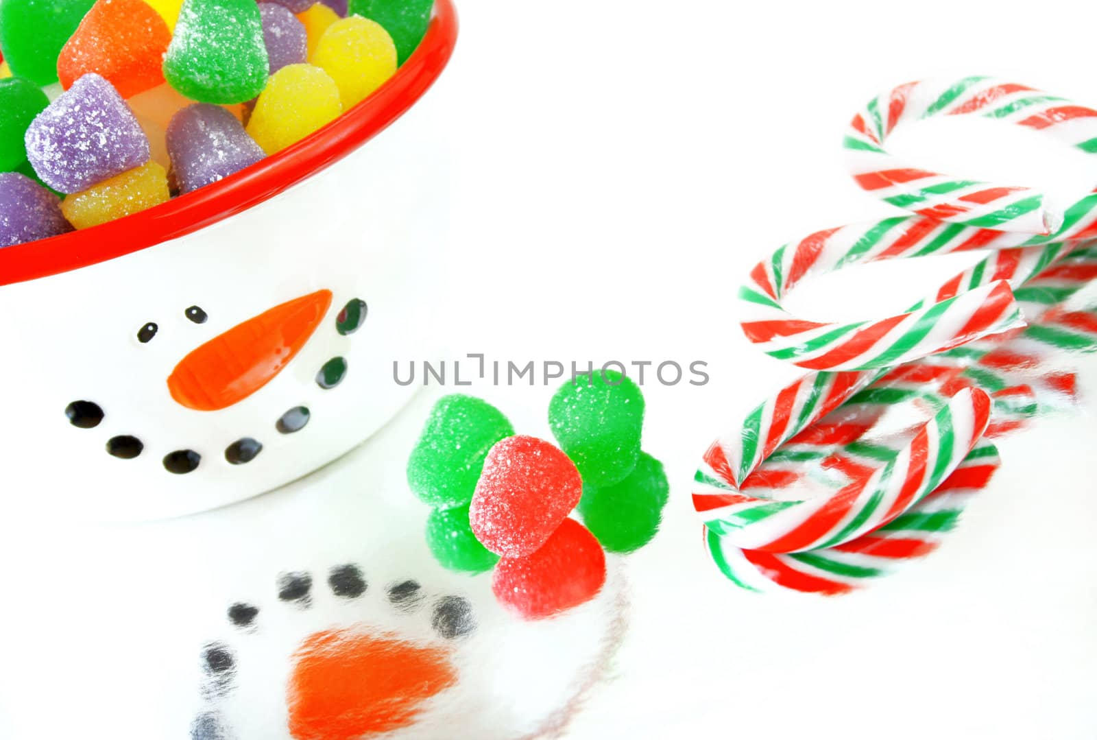 A high key image of Christmas candy.  Candy canes, spice gumdrops and a snowman candy dish.