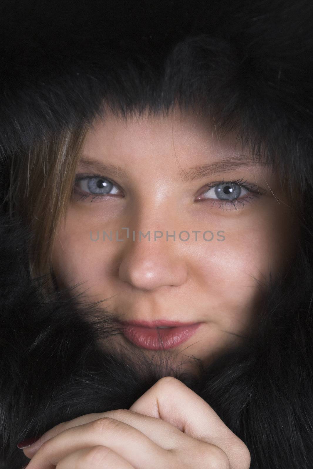 Head portraits of a pretty young lady hiding from frost in a black fur hood