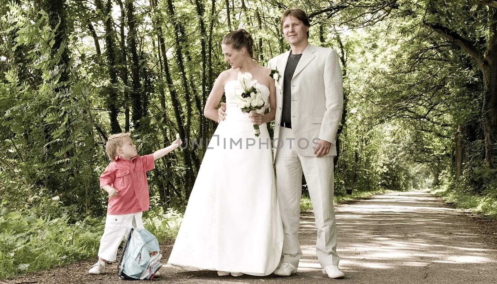 Young wedding couple's son presenting a flower to his parents