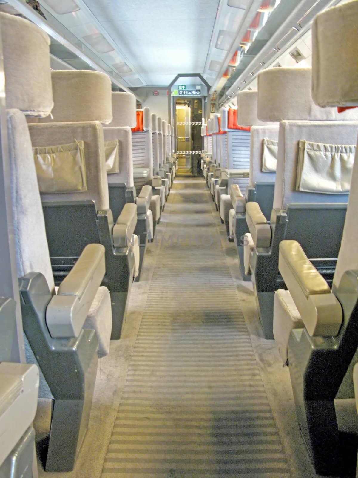 An aisle of a train with a lot of seats.