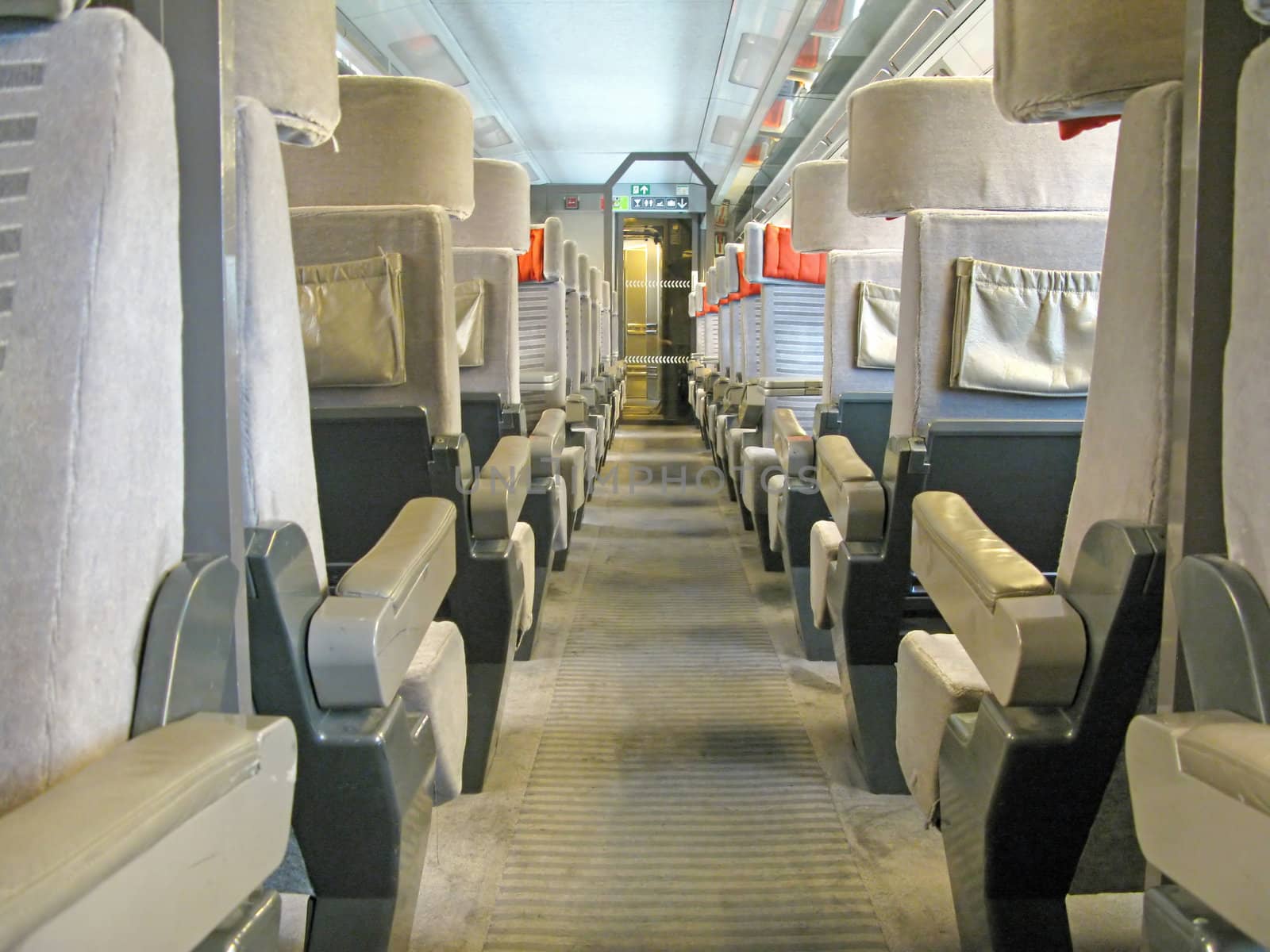 An aisle of a train with a lot of seats.