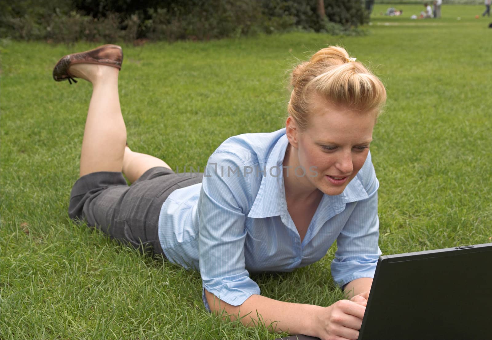 woman laying on the grass, working with laptop