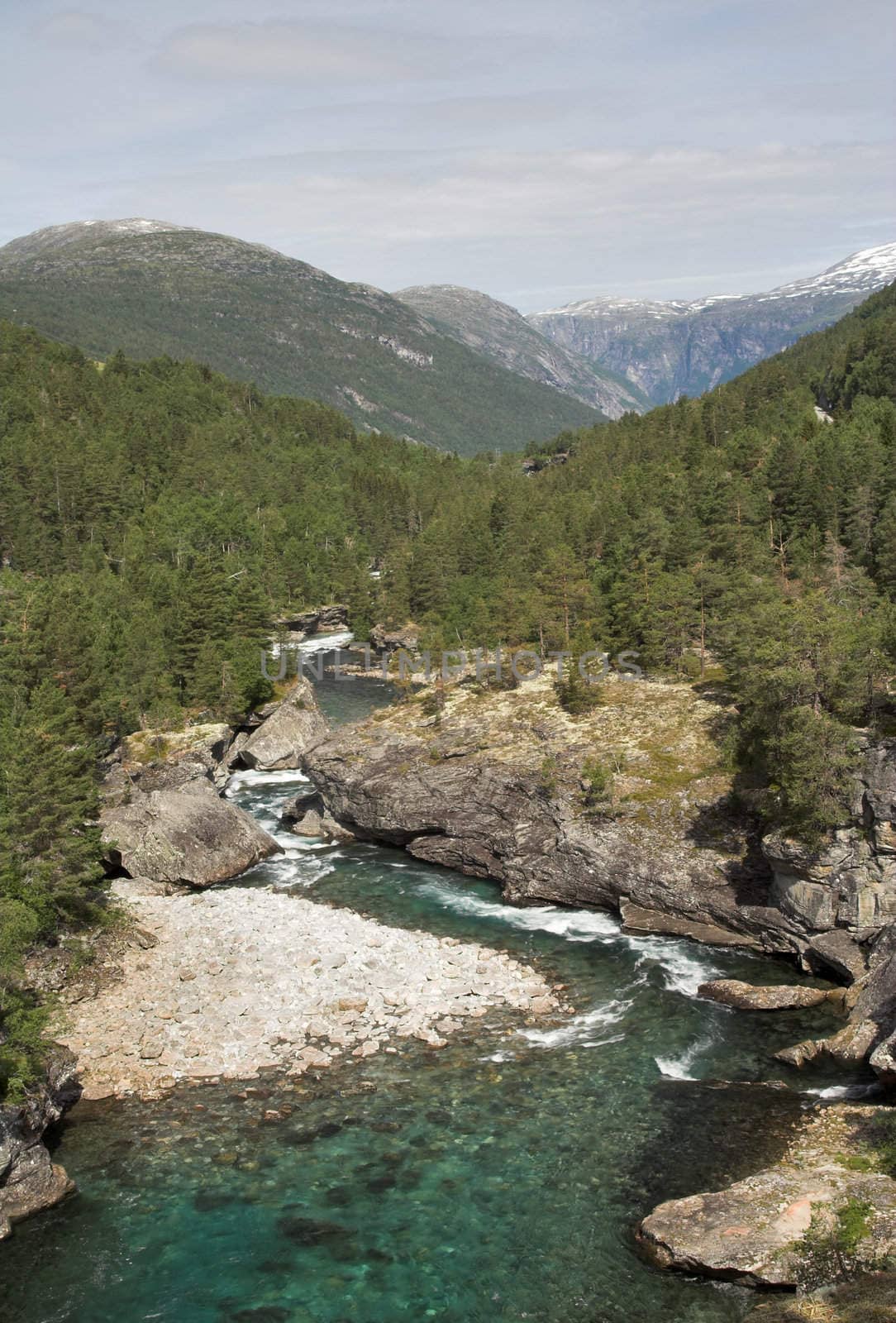 Turns of a mountain river; snow mountain tops in the background