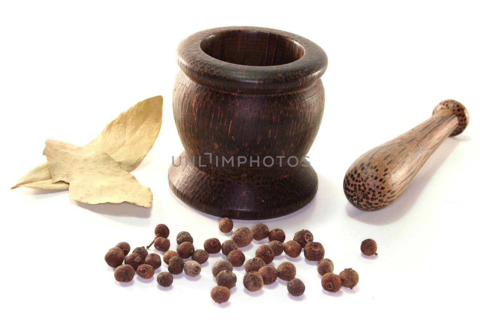 Mortar with bay leaves and allspice on a white background