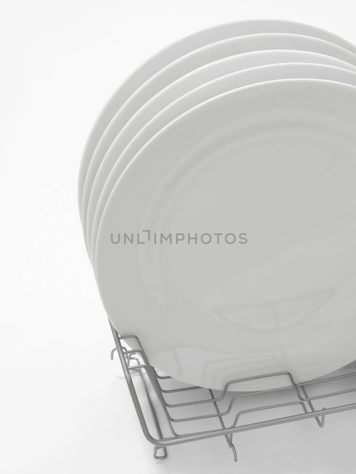 stack of white dining plates in drying rack