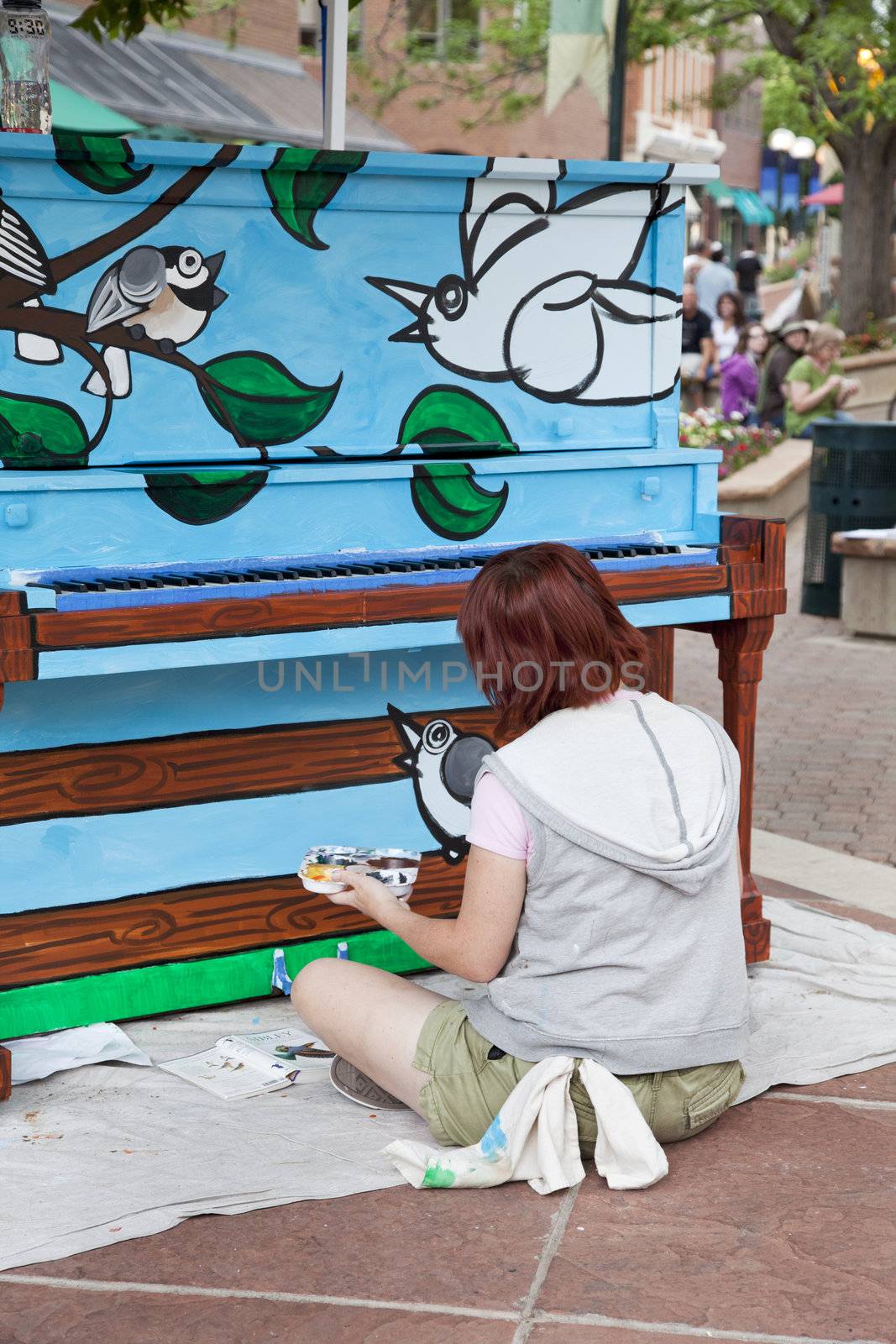 FORT COLLINS, COLORADO, USA - JUNE 18, 2011: Artist Ren Burke is painting a mural on the piano in Fort Collins Old Town Square as part of Pianos About Town public art program. June 18, 2011.