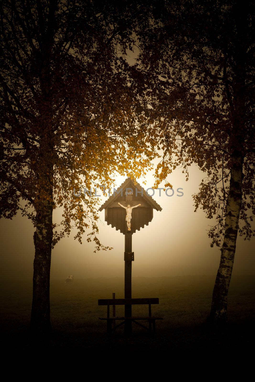 An image of a beautiful cross with fog in bavaria germany