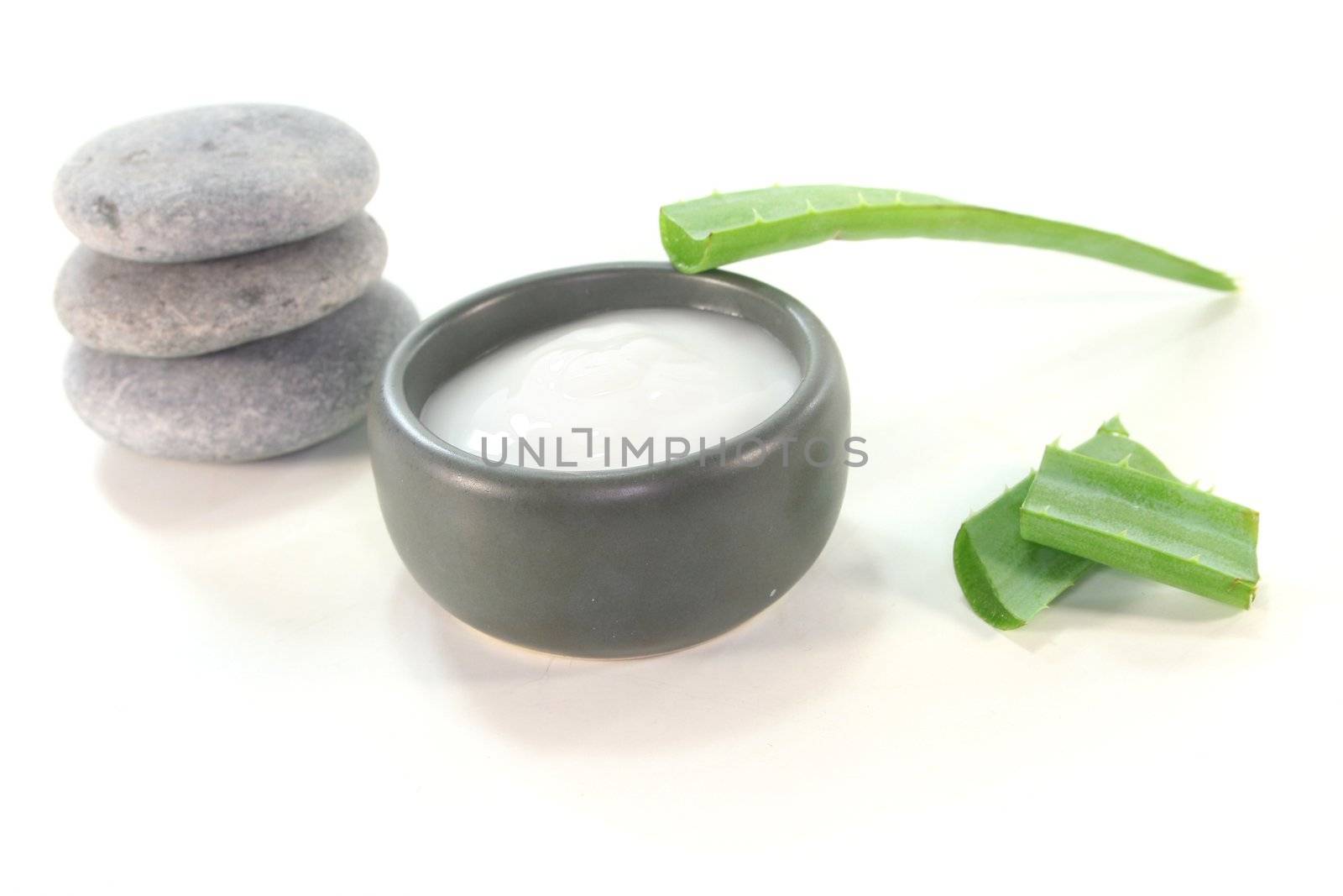 Aloe Vera lotion in a porcelain dish with aloe vera on a white background