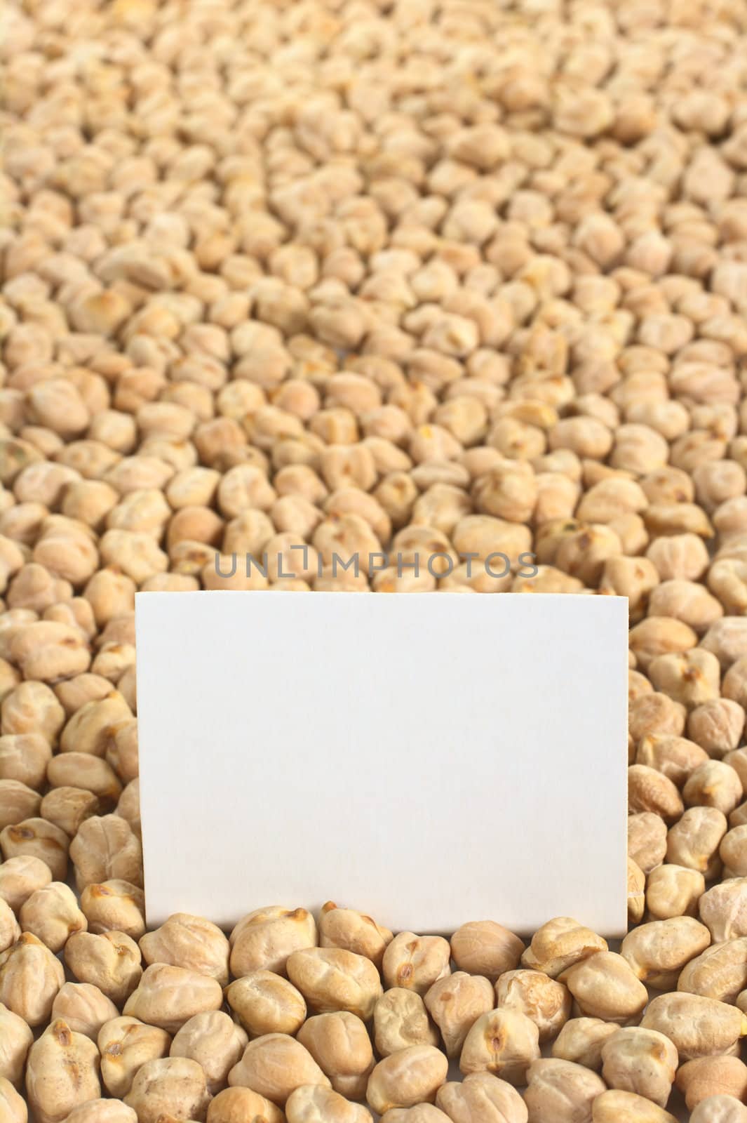 Raw white dried chickpeas (lat. Cicer arietinum) with a blank card (Selective Focus, Focus on the card)