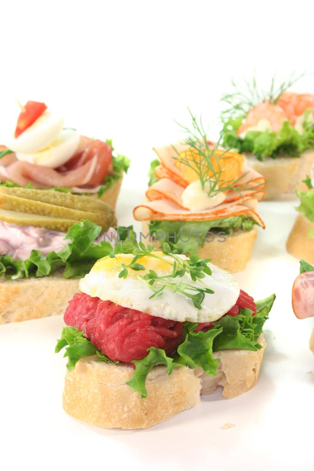 Canape with lettuce, sausages, meat salads, shrimp and quail eggs on a white background