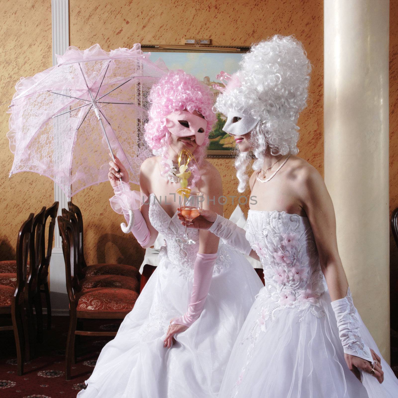 Two girls in wedding dresses and masks
