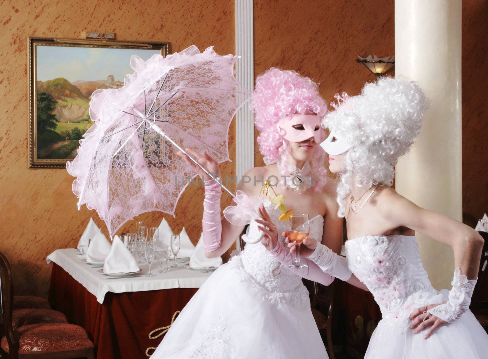 Two girls in wedding dresses and masks

