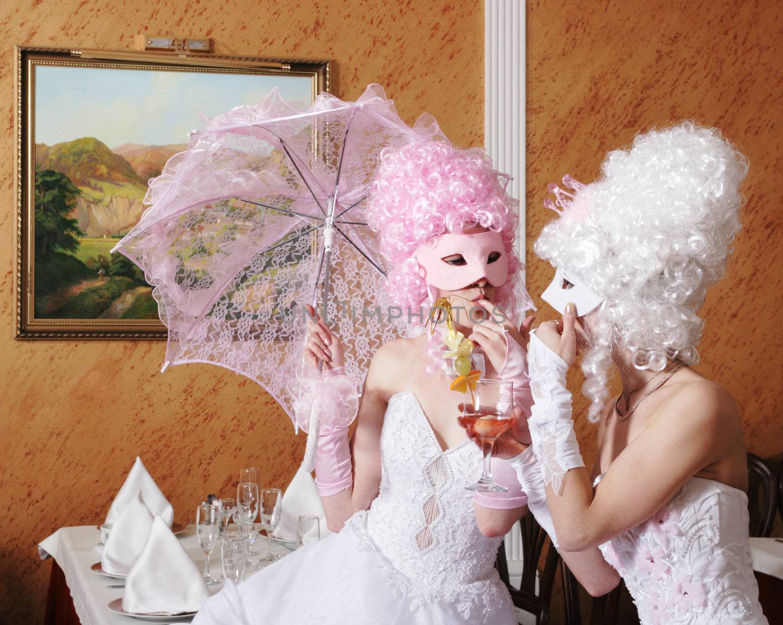 Two girls in wedding dresses and masks
