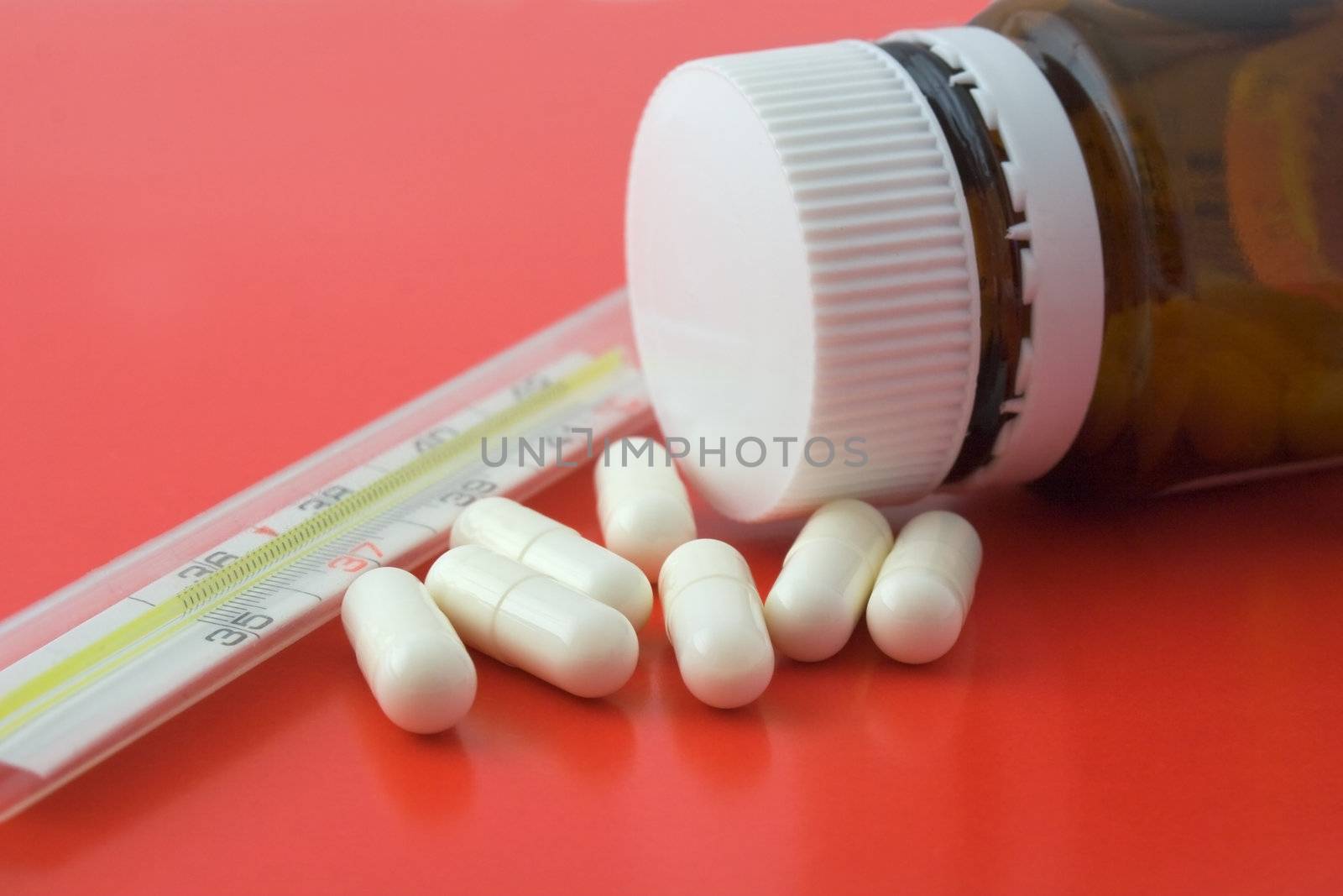 Bottel of pills and old thermometer on white background