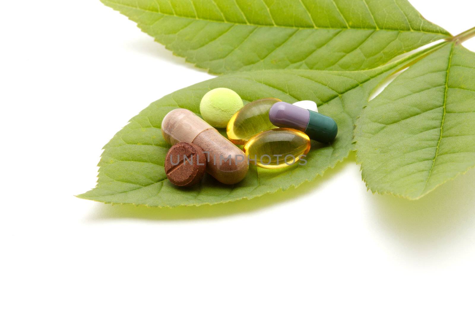 vitamins, tablets and pills on green leaf by rudchenko