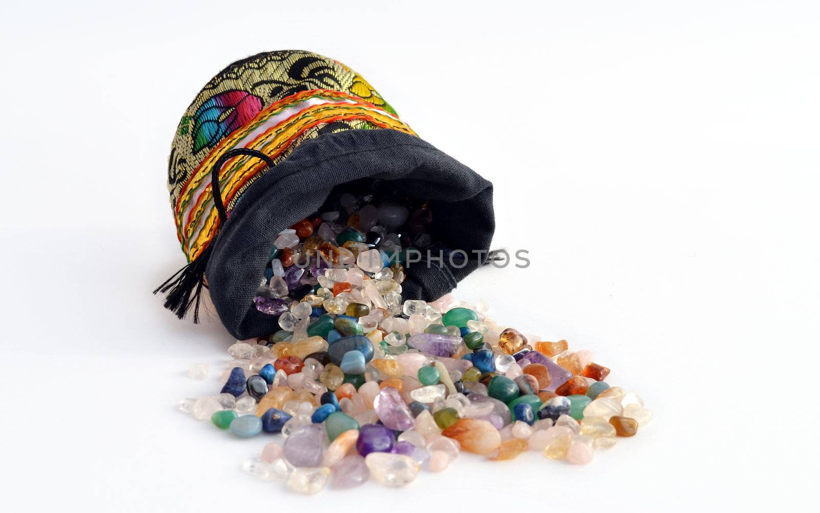 Quartz and other semiprecious pebbles pouring out of a decorated sacket 