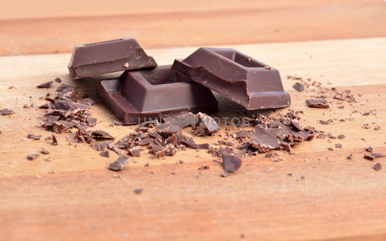 Chocolate squares and crumbles on wood surface
