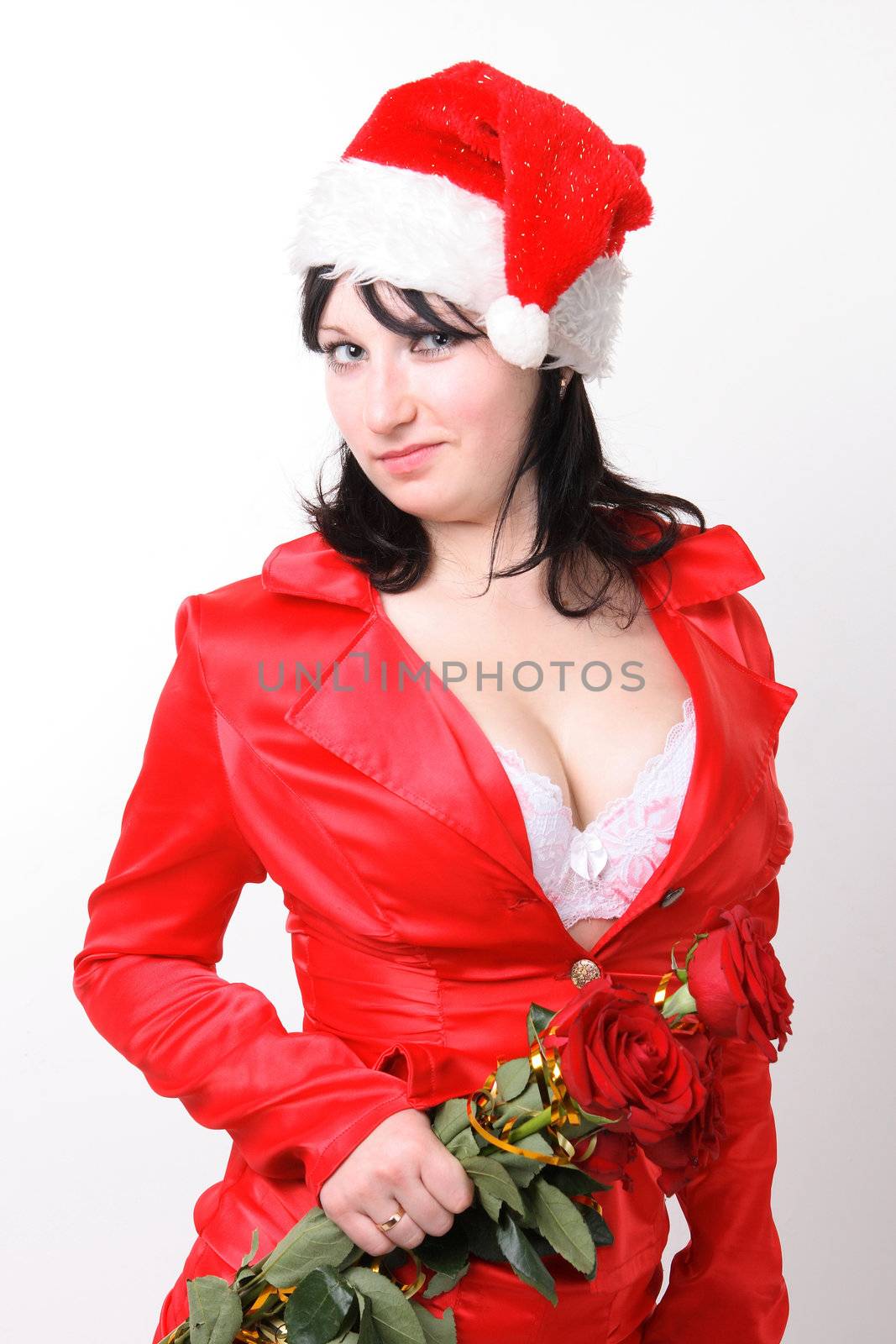 Portrait of a beautiful young woman in a red suit and hat of Santa Claus with red roses on the grey background
