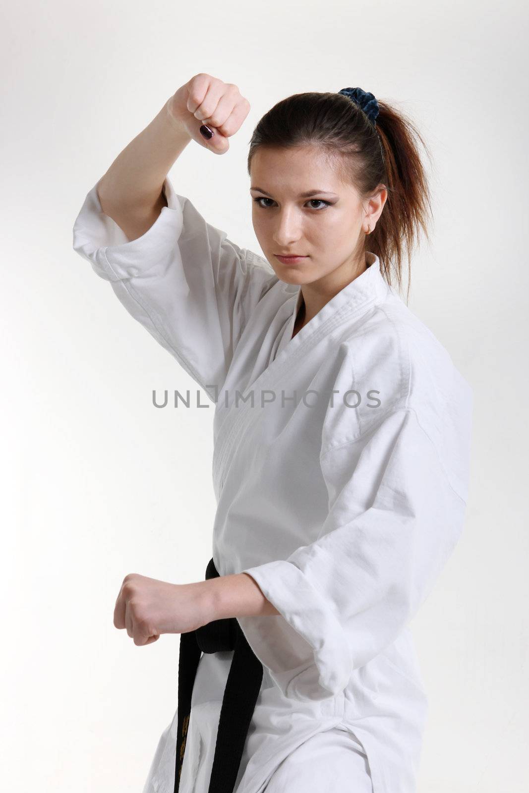 Karate. Young girl in a kimono with a white background
