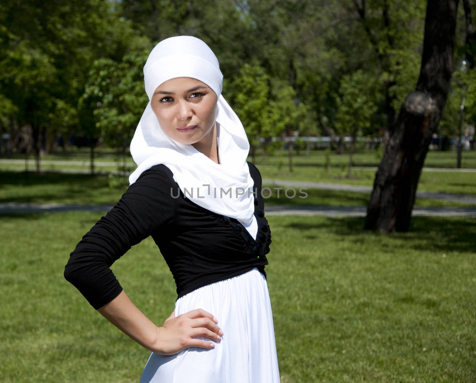 Portrait of young woman in park with a white scarf on a head