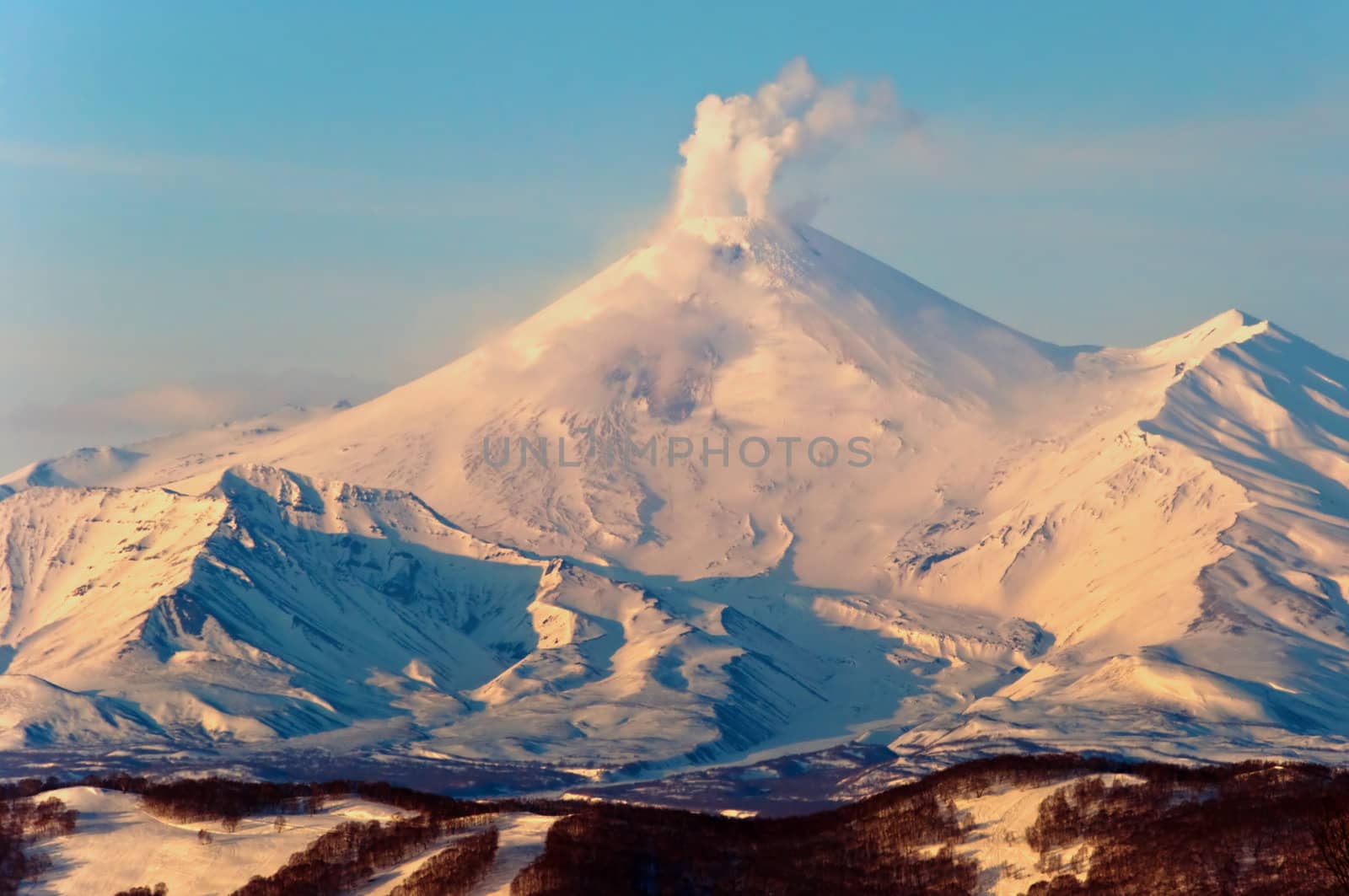 Beautiful snow-covered volcano a letting out smoke from a crater