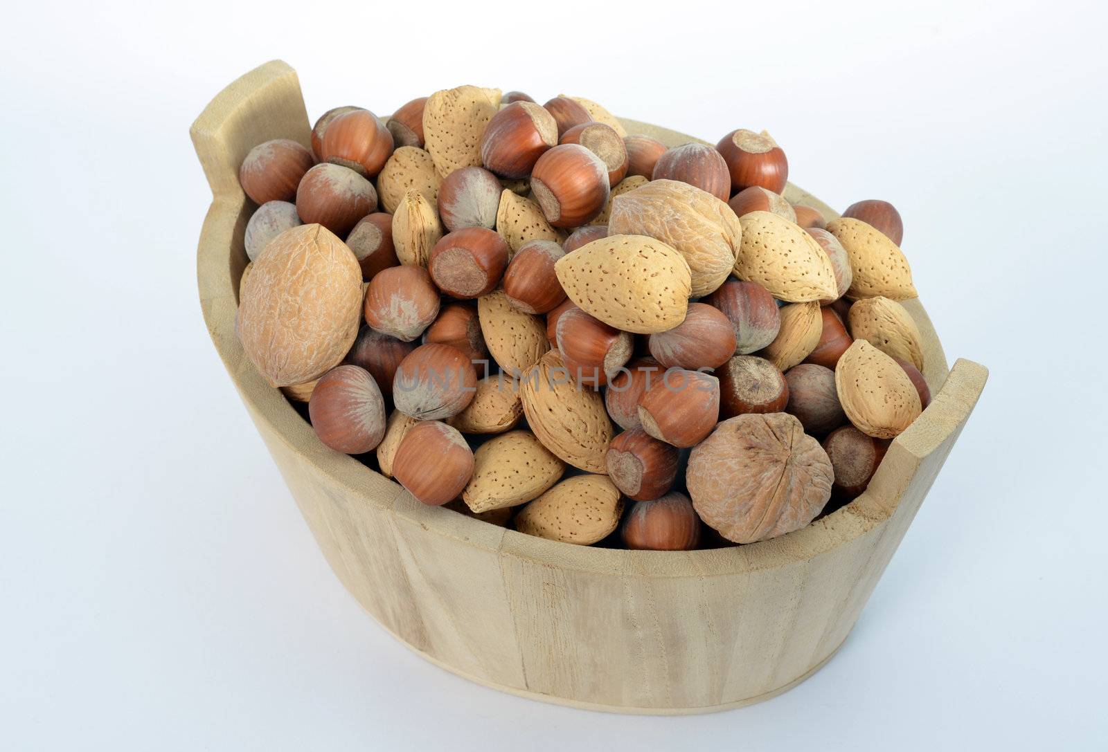 Hazelnuts, walnuts and almonds in a wood basket isolated on white background