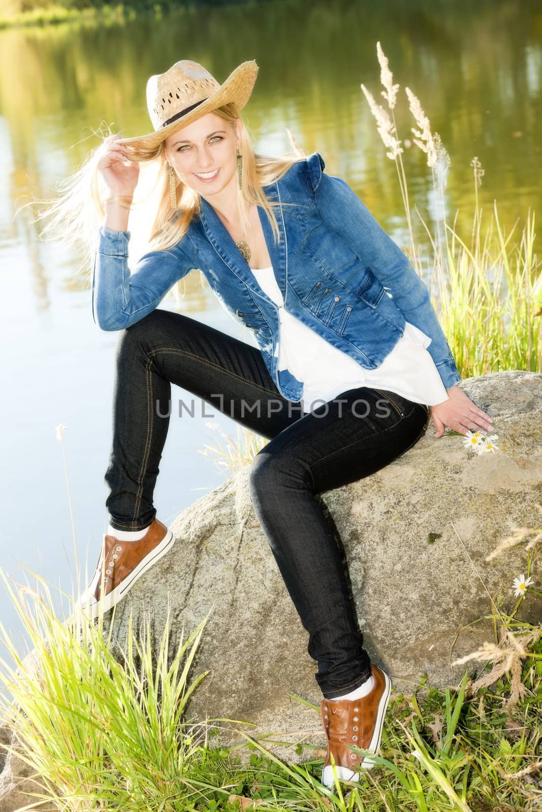 young woman sitting on stone at pond by phbcz