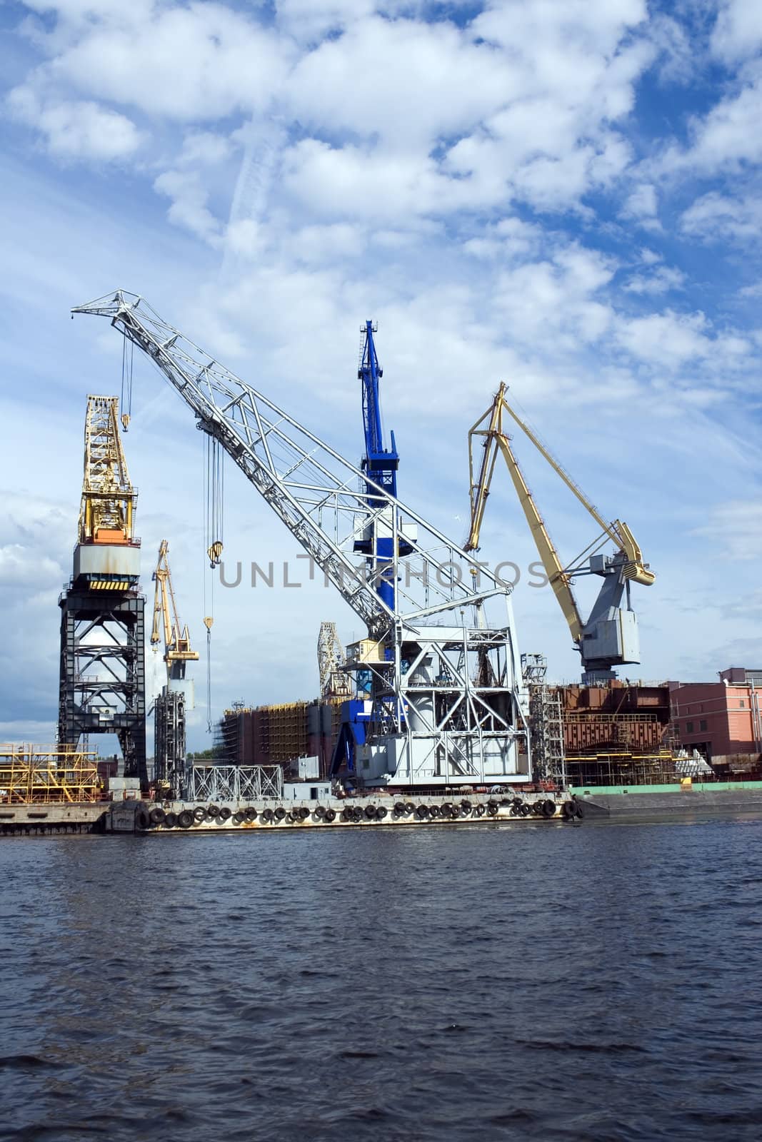 Large construction cranes in shipyard.