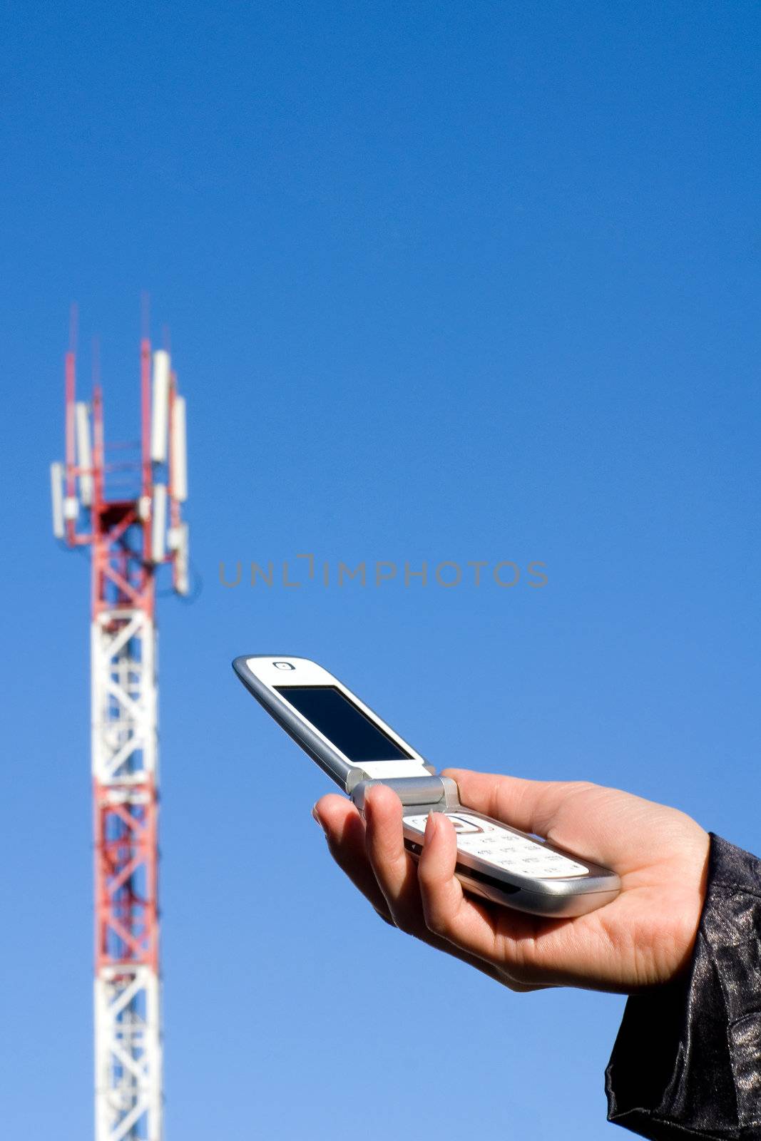Cellular telephone in a hand against the GSM base station