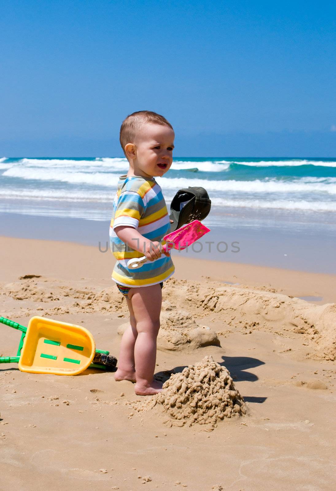 One year old child building sand castle on the beach