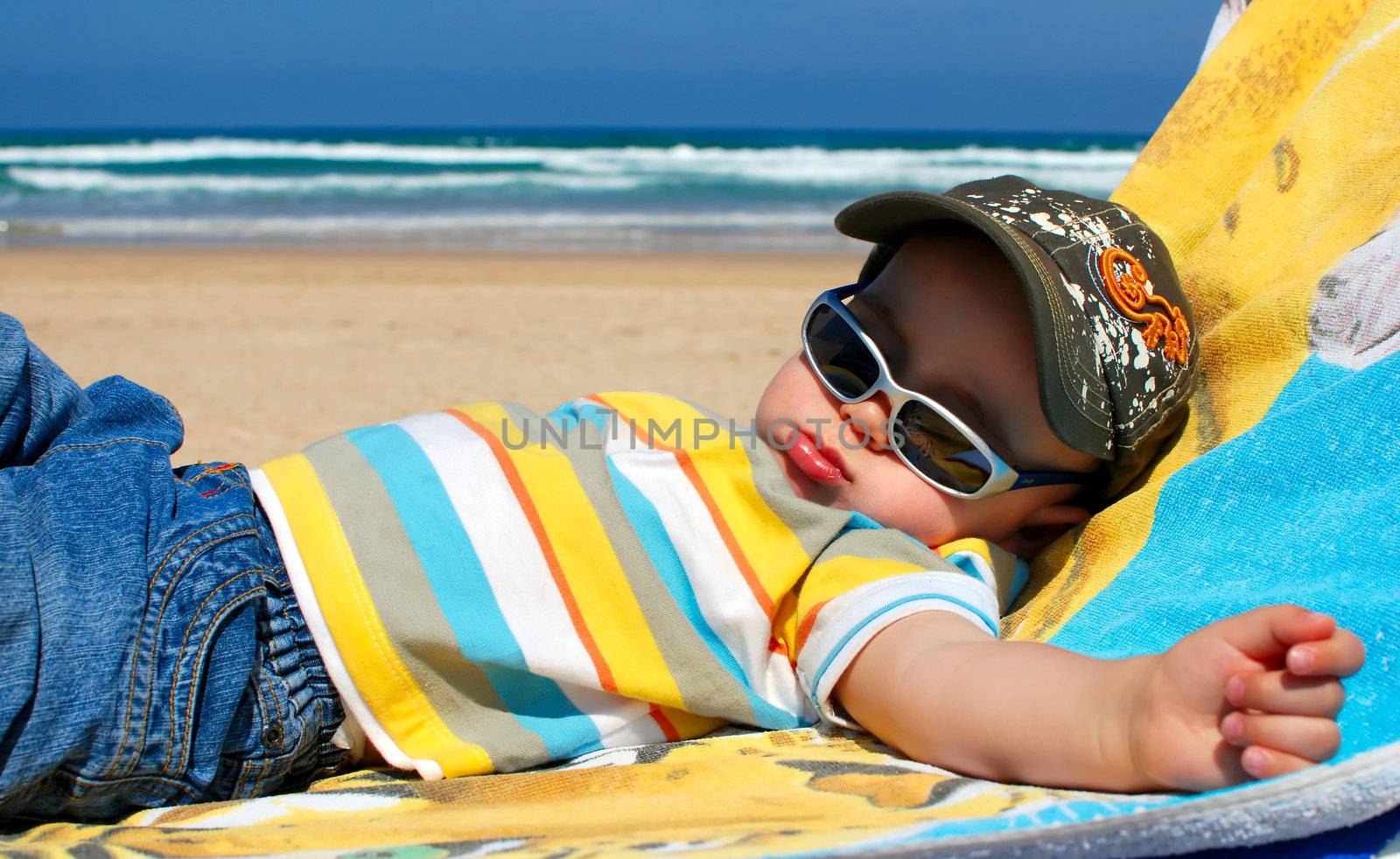 Portrait of one year old boy sleeping on beach