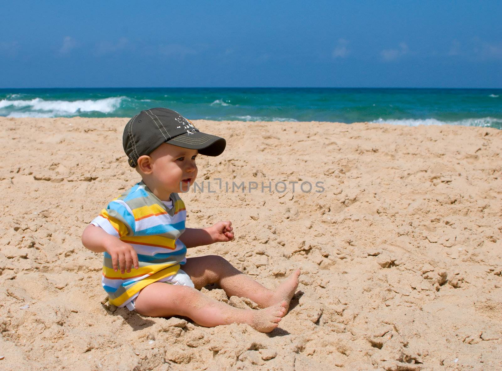 One year old boy sitting on sand 