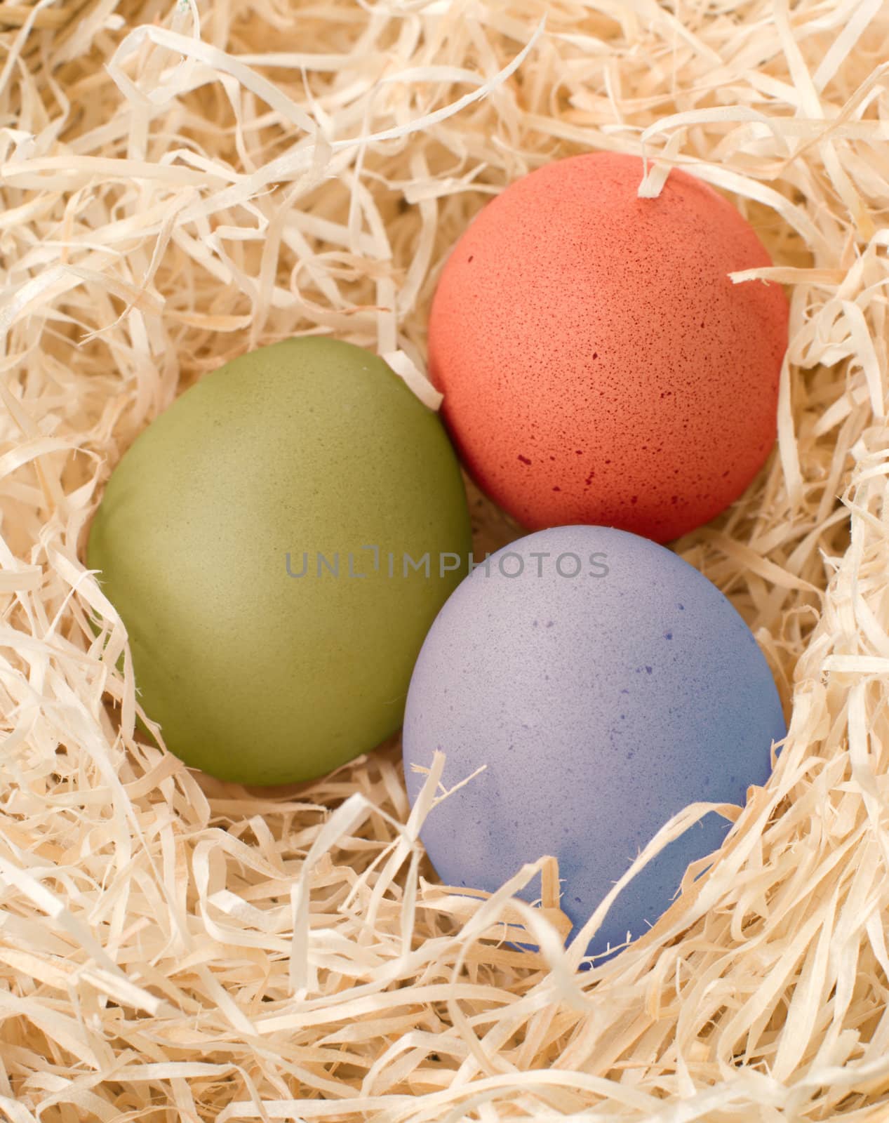 three easter colour eggs in nest 