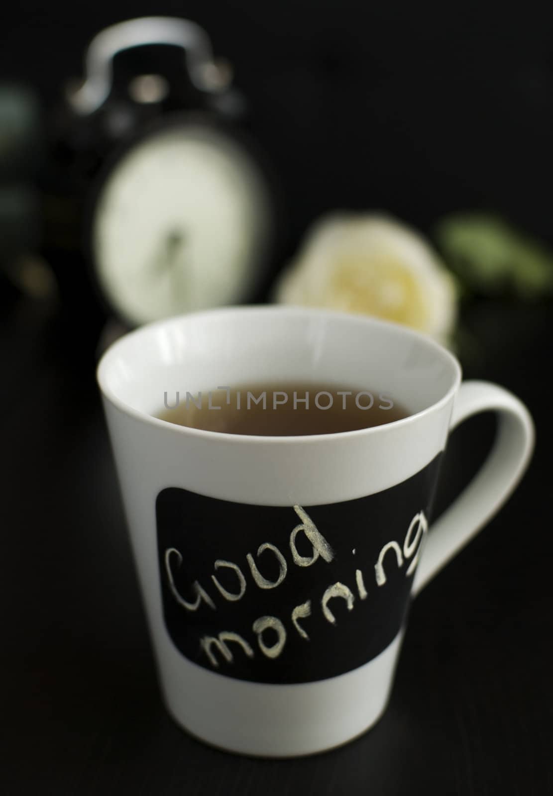 cup of tea, rose and clocks in background 