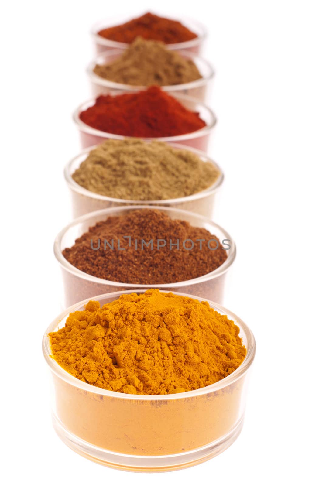 collection of indian spices (cumin, coriander, paprika, garam masala, curcuma, chili powder) on glass cups isolated on white background (shallow DOP, focus on first)