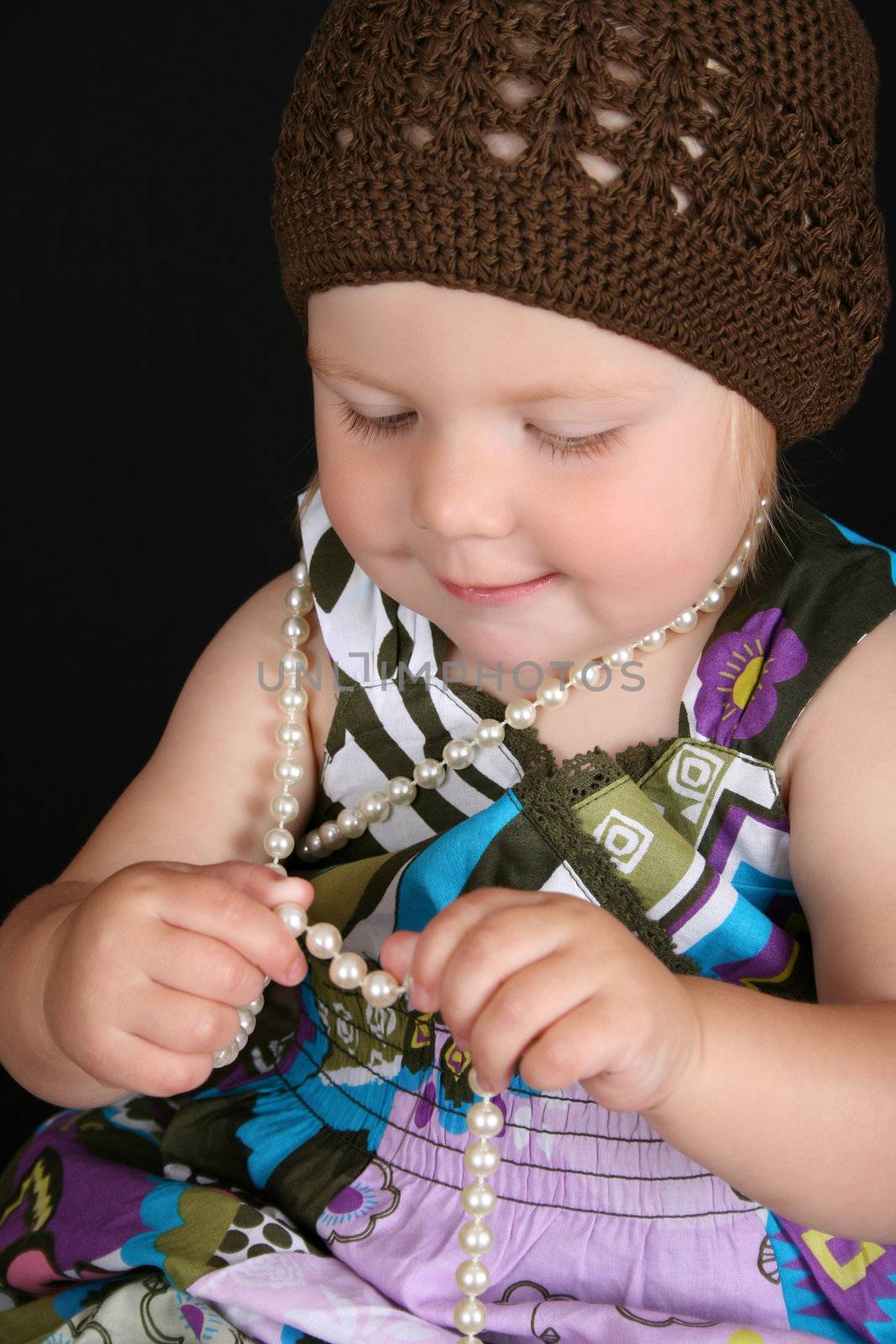 Beautiful toddler playing with a string of pearls