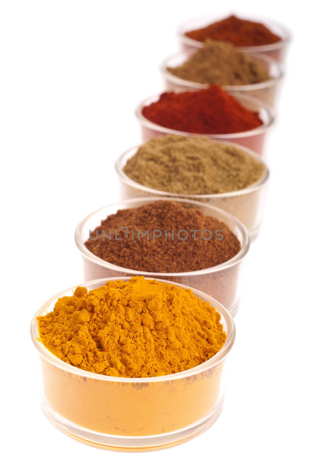 collection of indian spices (cumin, coriander, paprika, garam masala, curcuma, chili powder) on glass cups isolated on white background (shallow DOP, focus on first)