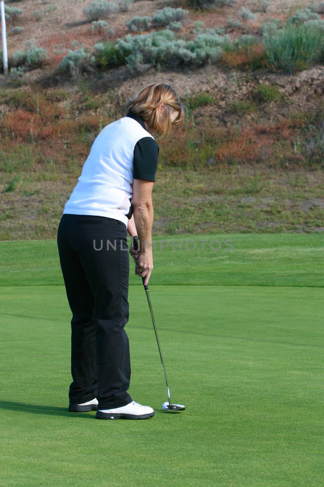 Blond female golfer putting on the green
