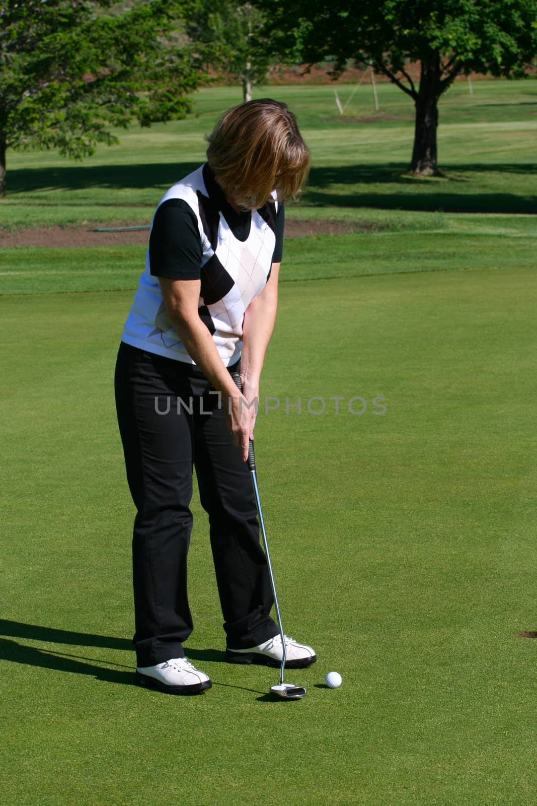 Blond female golfer putting on the green
