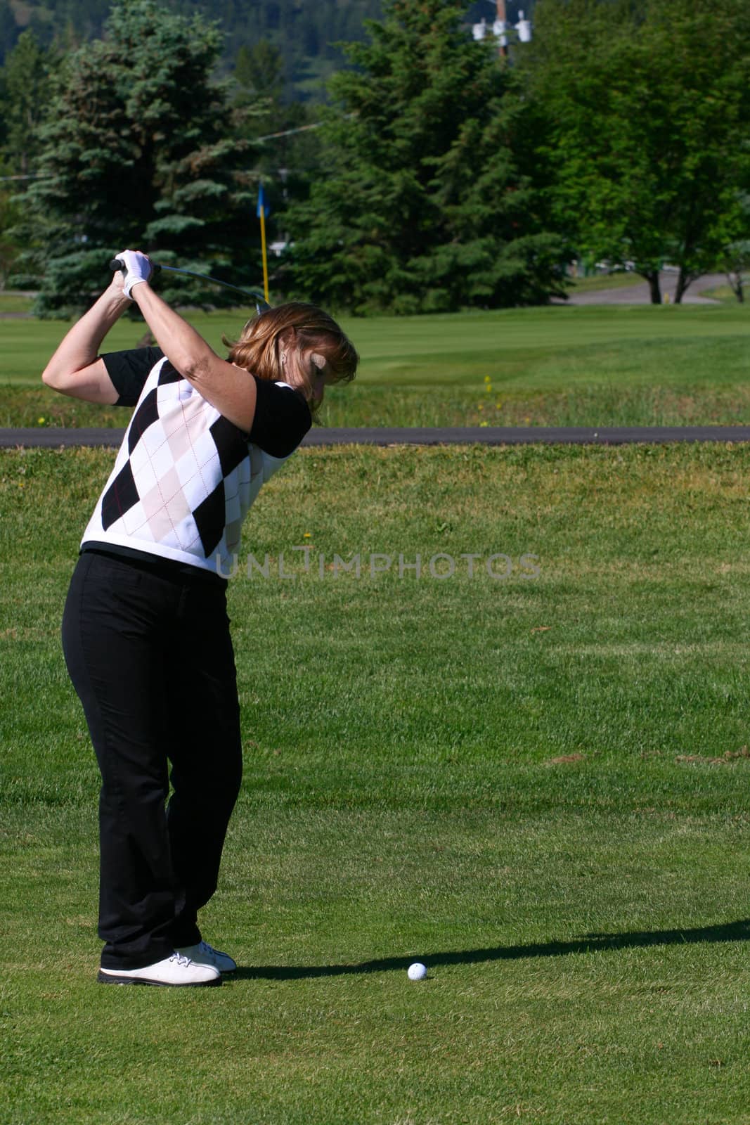 Adult female golfer playing an iron shot from the fairway