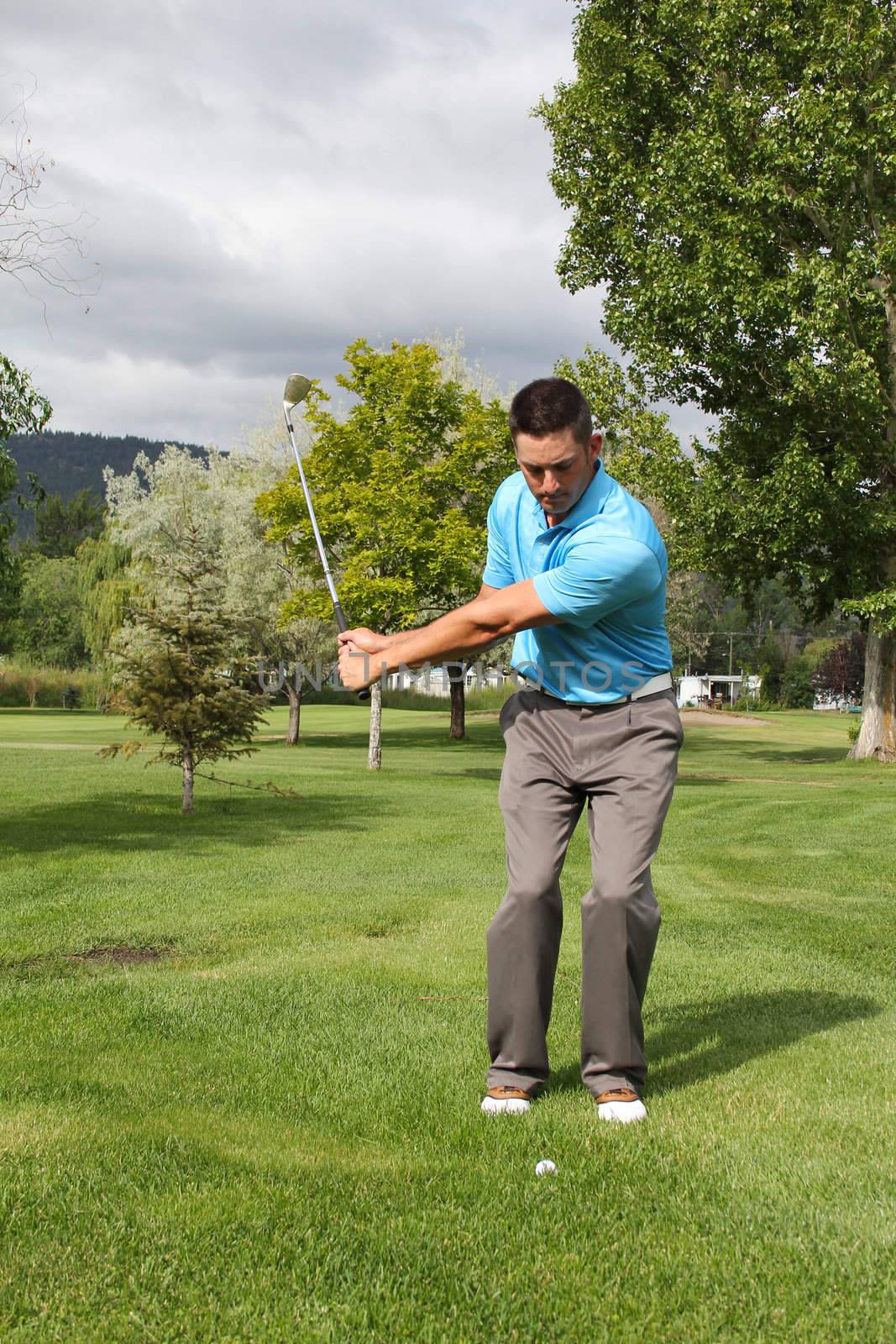 Young golfer playing a chip shot from the rough