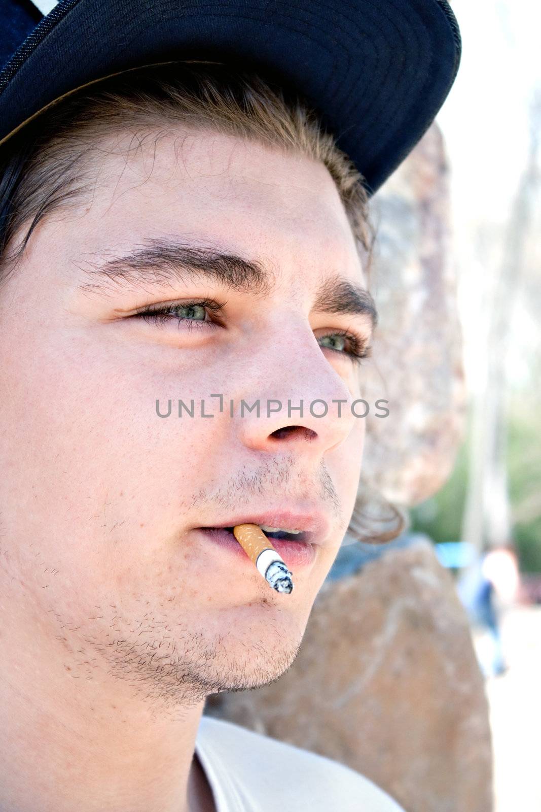 Close up of a young man in his early twenties smoking a cigarette.