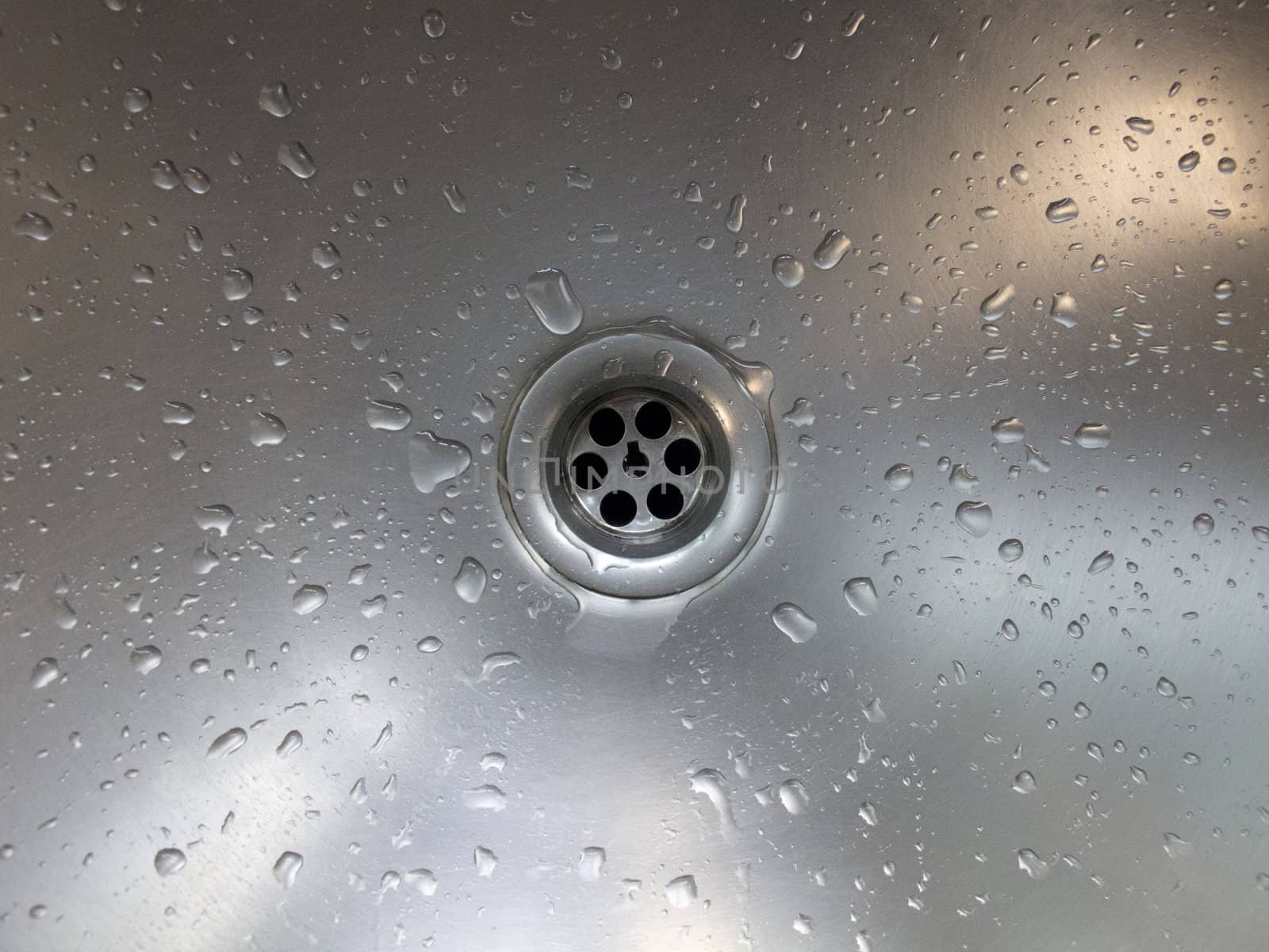 A drain of aluminium basin with drops of water.