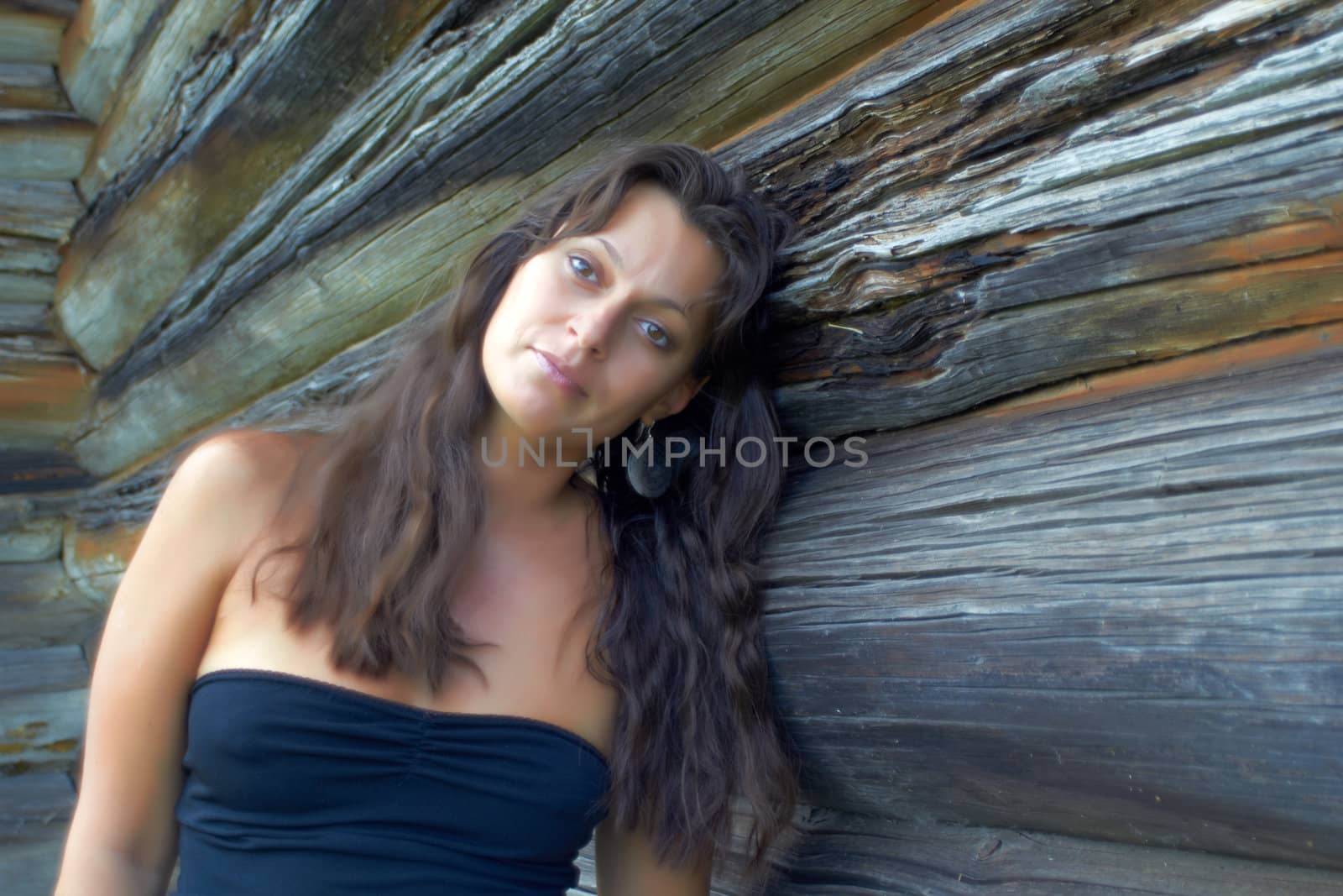 Beautiful brunette woman near the old wooden wall