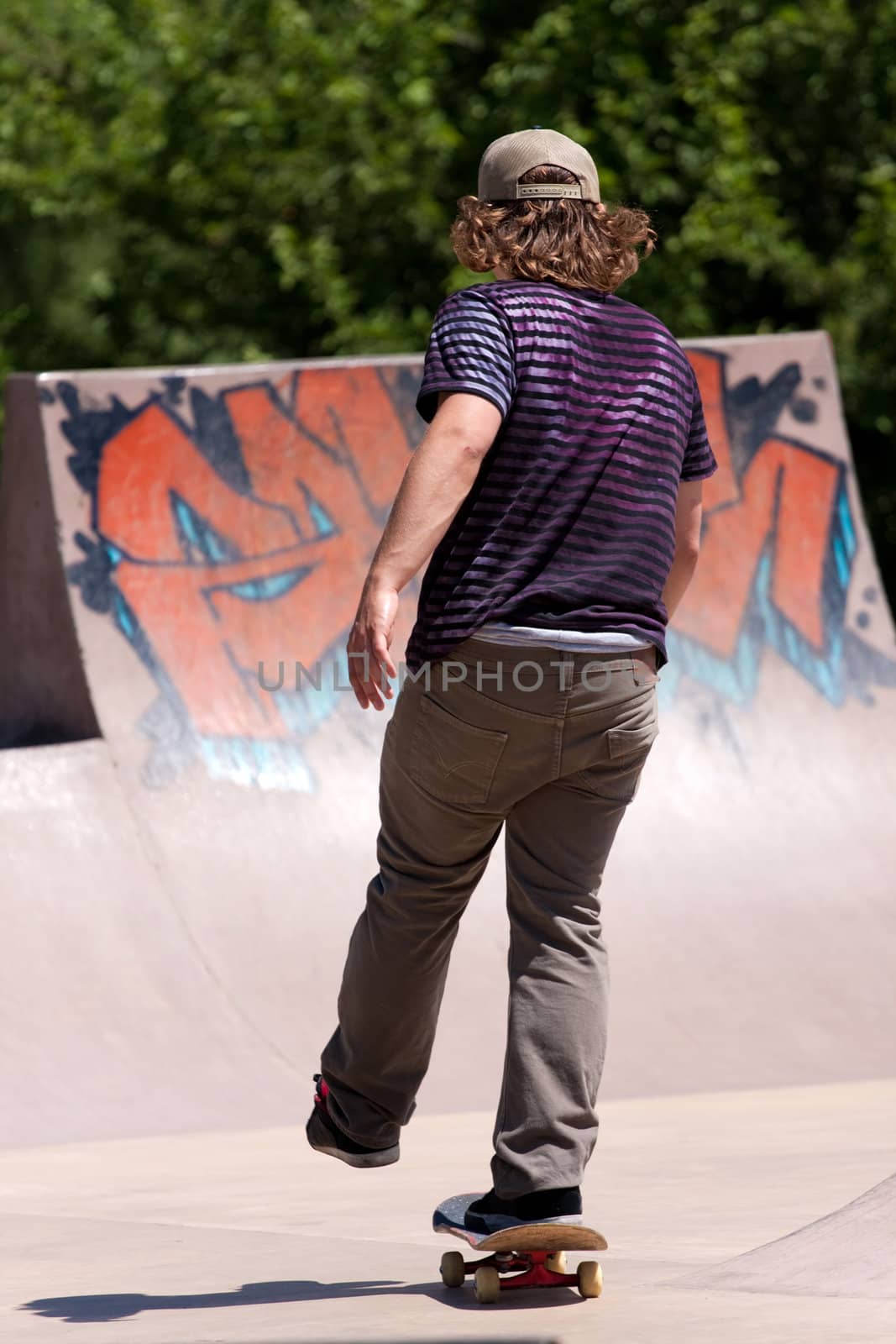 Action shot of a skateboarder skating at the skate park towards the concrete ramps.