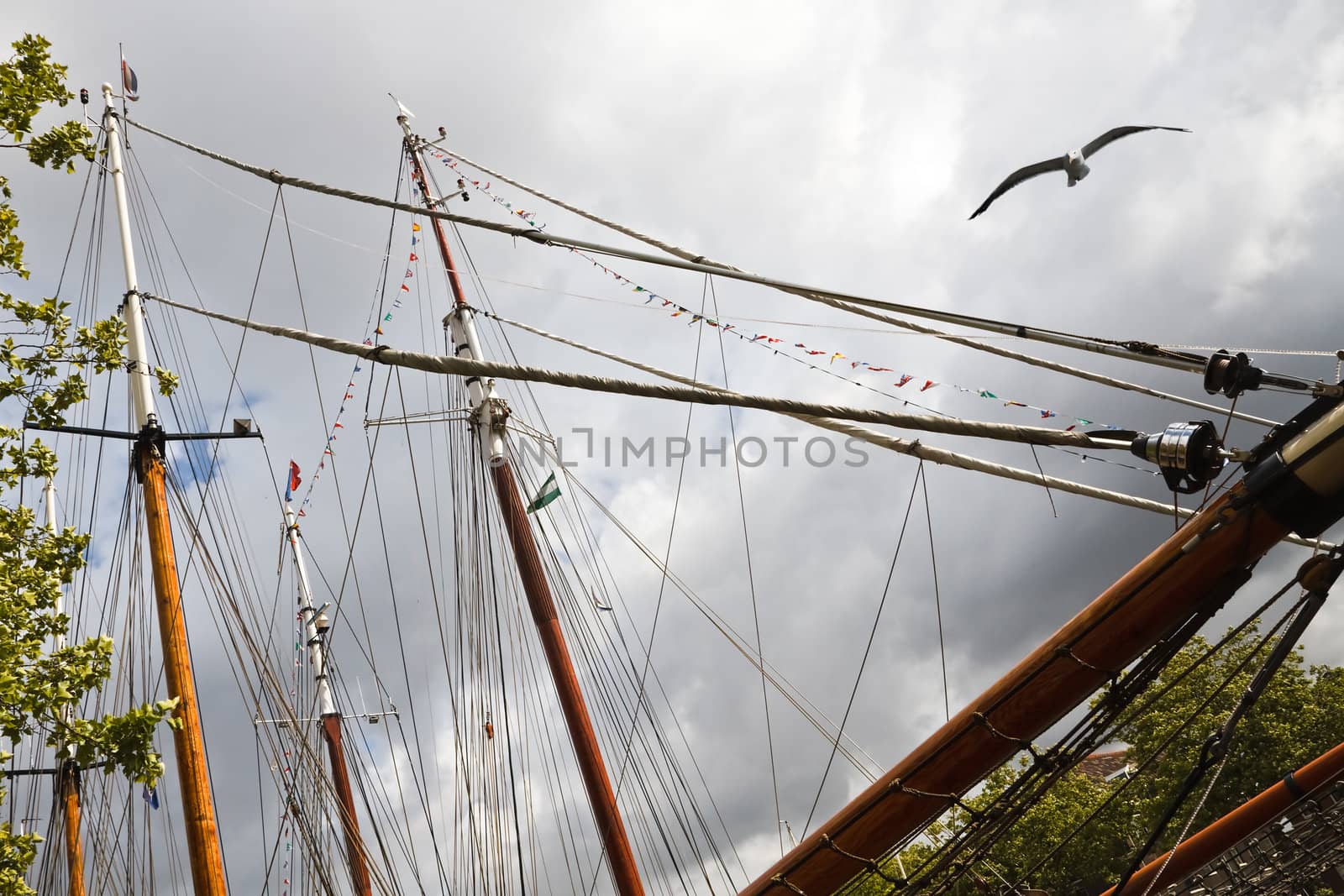 Masts, ropes and flags on sailing ships with rainclouds in background