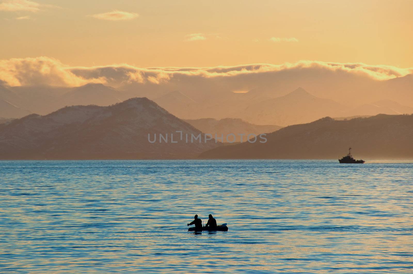 Fishermen by a boat in an evening bay