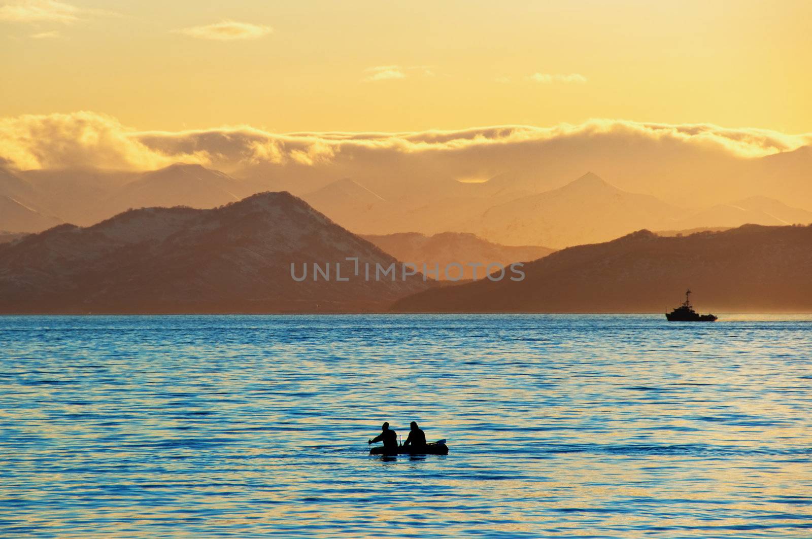 Fishermen by a boat in an evening bay