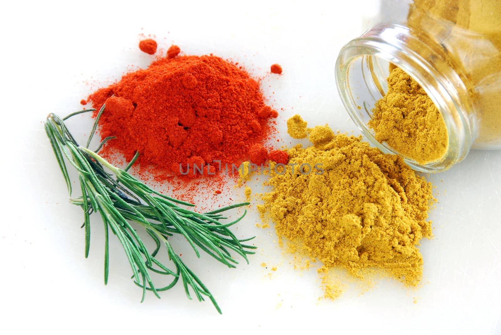 red paprika and curry heaps with rosemary branch on white background